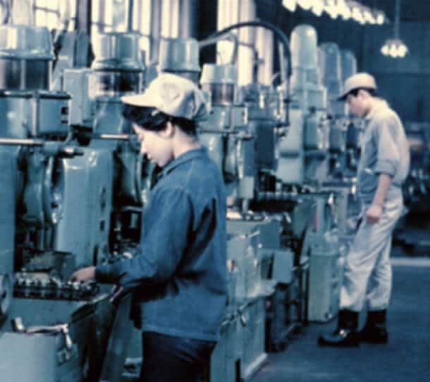 A Woman Operating Industrial Manufacturing Machinery On A Mid Century Factory Floor