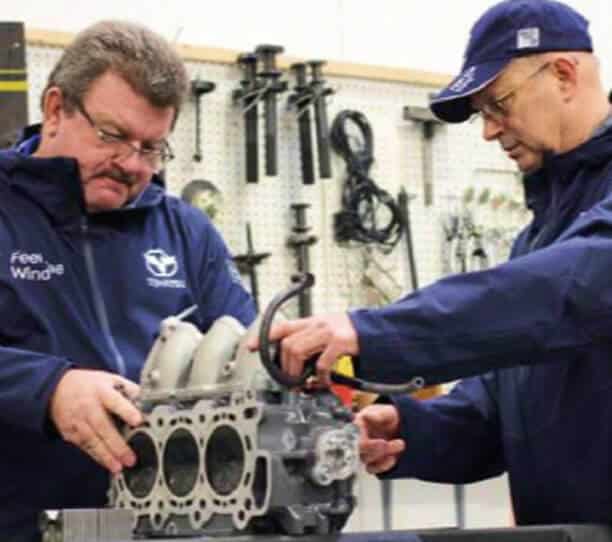 Two Mechanics Inspecting A Car Engine Block In A Modern Workshop
