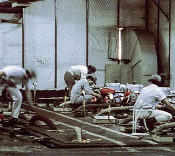 Vintage Photo Of Factory Workers Assembling Machinery On An Early Automotive Production Line